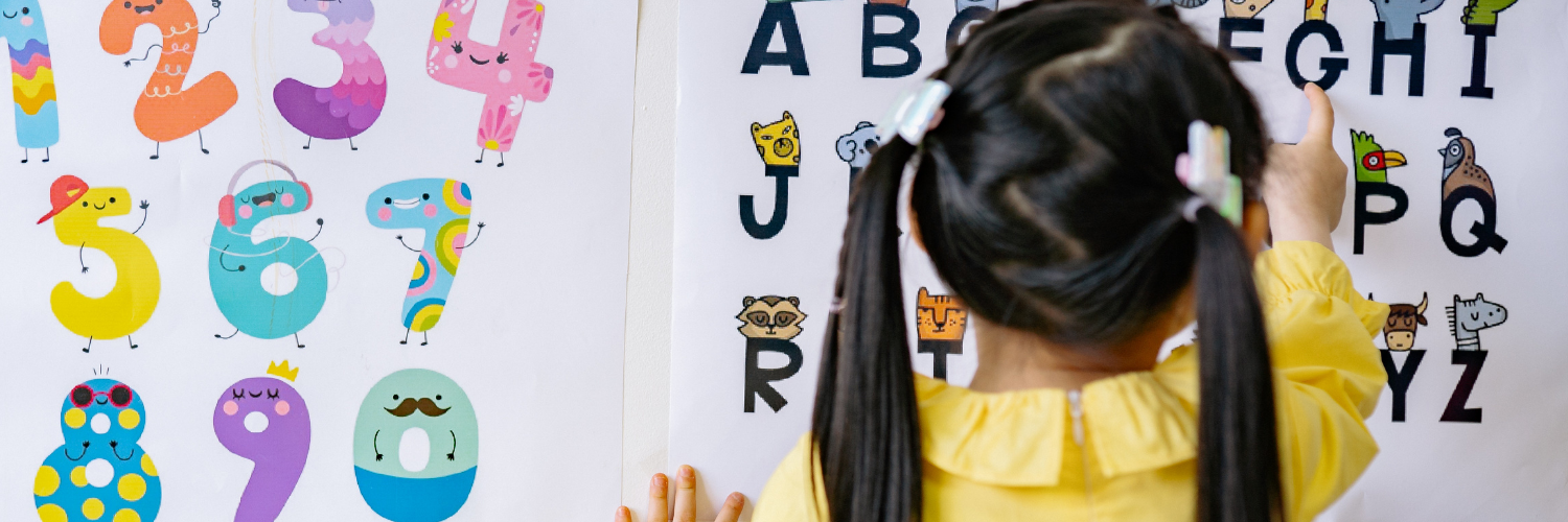 Female teacher points at a workbook and explains what her pupils need to complete